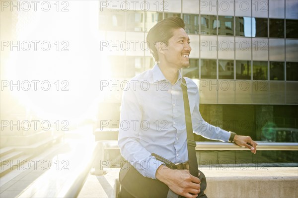 Smiling Mixed Race businessman walking outdoors on sunny day