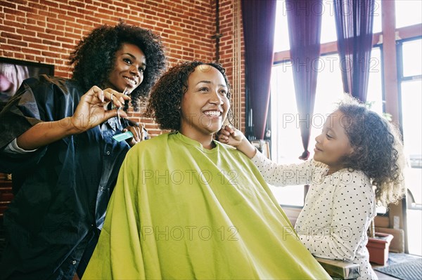 Smiling hairdresser and customers in hair salon