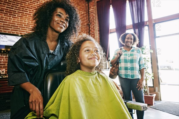 Smiling hairdresser and customers in hair salon