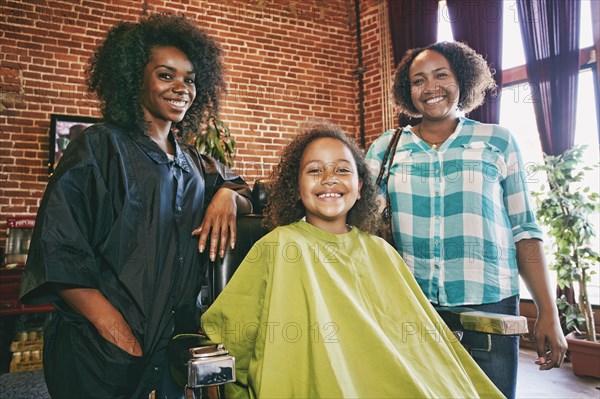 Smiling hairdresser and customers in hair salon