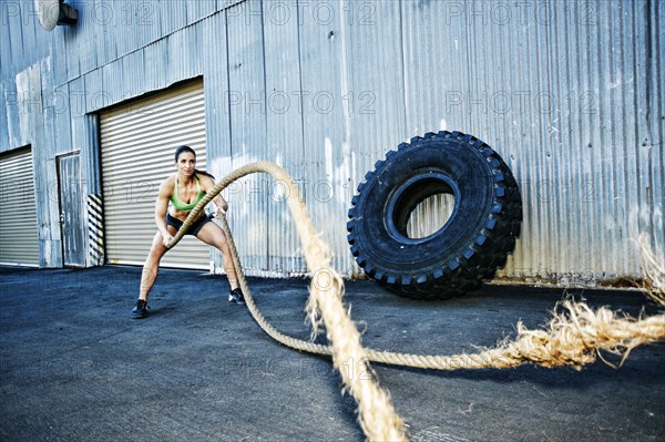 Mixed Race woman working out with heavy ropes outdoors