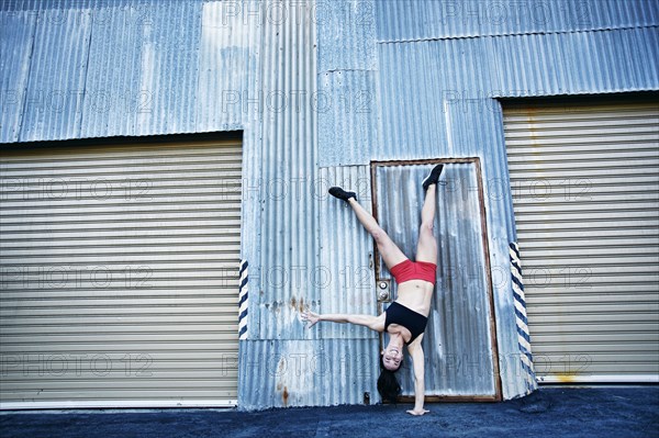 Caucasian woman doing one-handed handstand outdoors