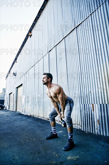 Caucasian man lifting kettlebell outdoors