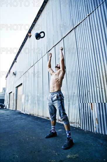 Caucasian man throwing kettlebell outdoors