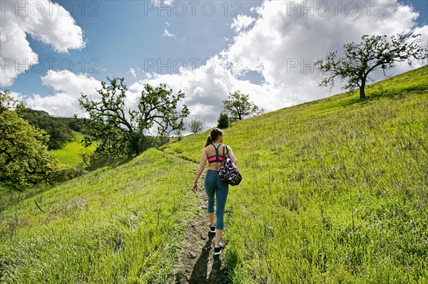 Caucasian woman walking on hill carrying bag