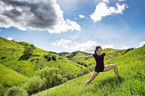 Caucasian woman doing yoga on hill