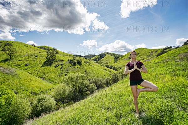 Caucasian woman doing yoga on hill