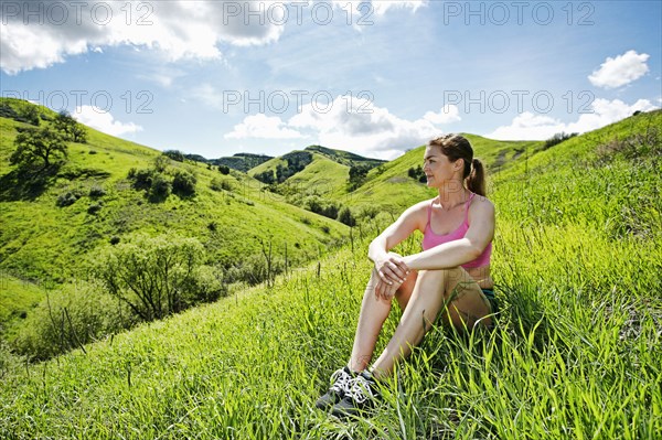 Pensive Caucasian woman sitting on hill