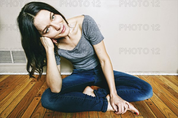 Smiling Caucasian woman sitting cross-legged on floor