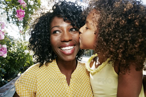 Daughter kissing cheek of mother outdoors