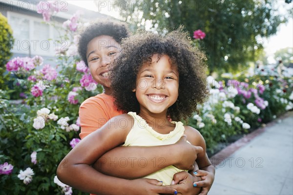 Mixed Race brother hugging sister outdoors