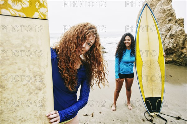 Smiling women holding surfboards at beach