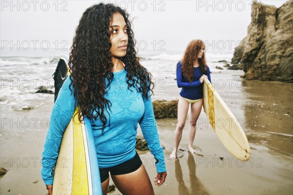 Serious women holding surfboards at beach