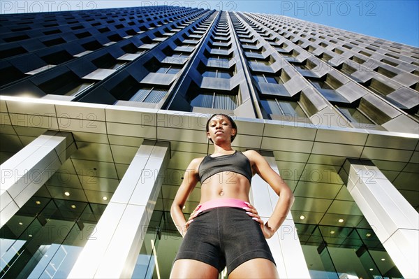 Serious Black woman standing under modern building