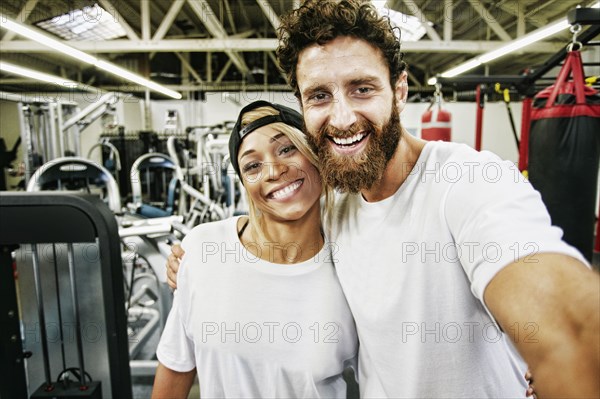 Mixed Race man couple posing for cell phone selfie in gymnasium