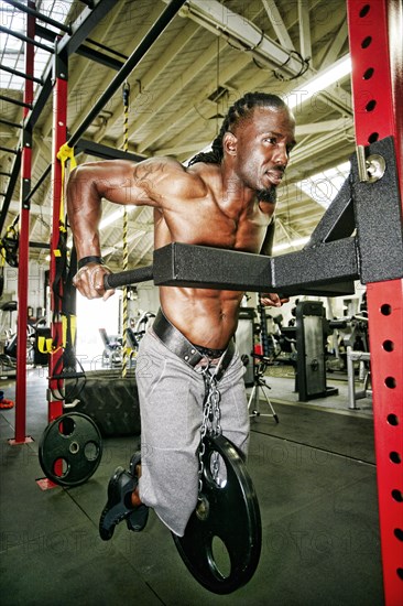 Black man doing weighted push-up in gymnasium