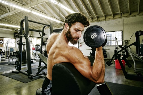 Mixed Race man lifting dumbbell in gymnasium