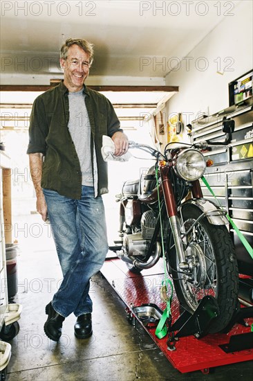 Caucasian man posing with motorcycle in garage