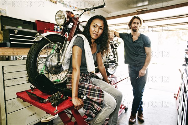 Serious man and woman posing with motorcycle in garage