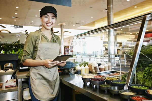 Mixed Race food court worker using digital tablet