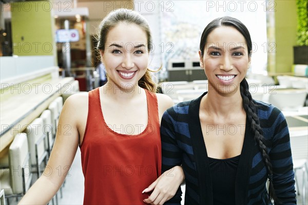 Smiling Mixed Race women posing in food court