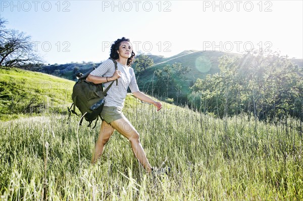 Smiling Mixed Race woman hiking on hill