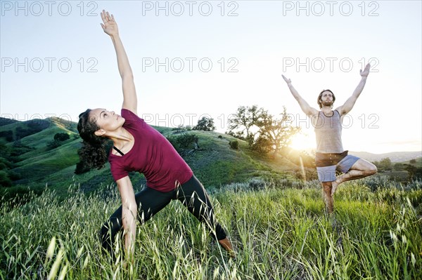 Couple practicing yoga on hill