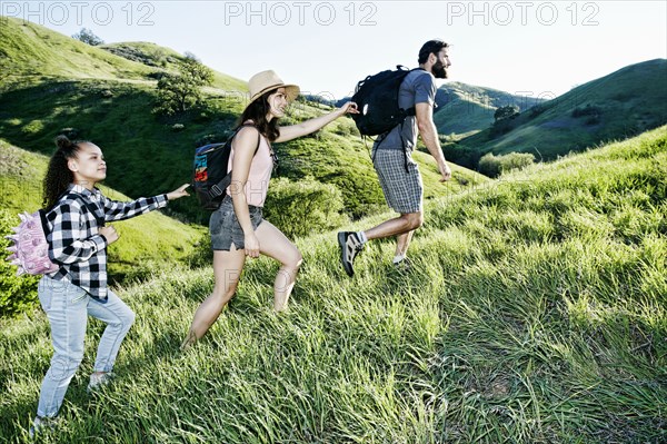 Father leading mother and daughter uphill