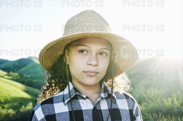 Pensive girl wearing hat on sunny hill