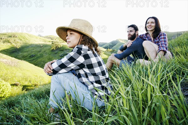 Family sitting on hill looking away