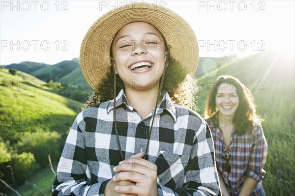 Portrait of mother and daughter laughing on hill