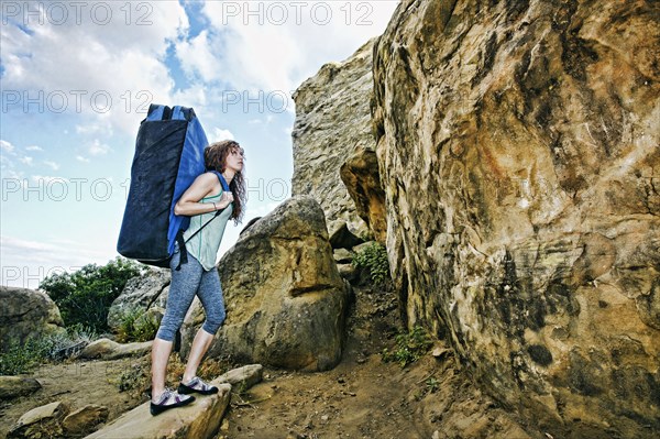 Caucasian woman carrying large backpack near rock formation