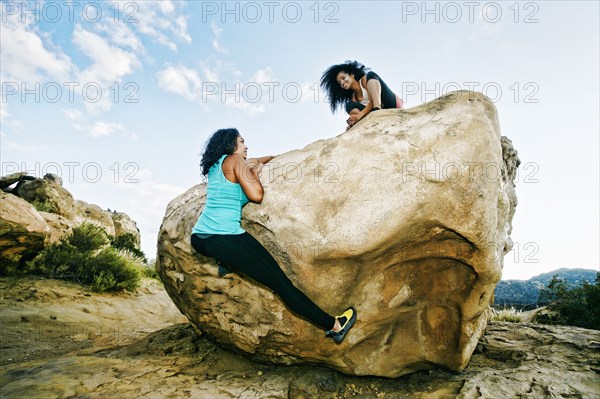 Women climbing on boulder