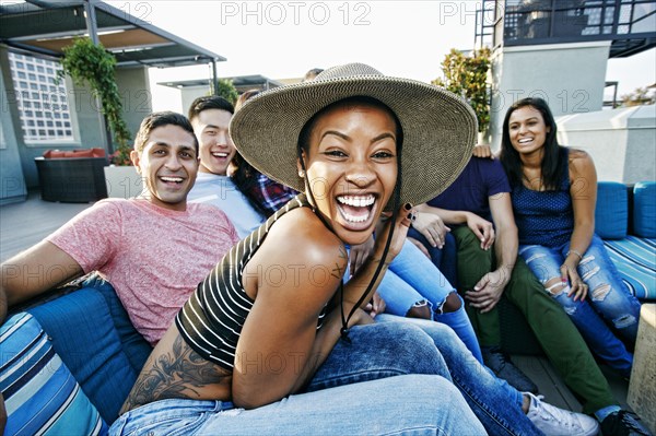 Friends laughing on rooftop sofa