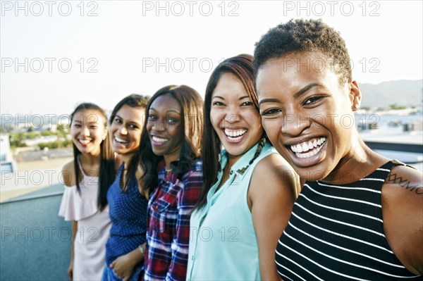 Smiling women standing in a row on rooftop