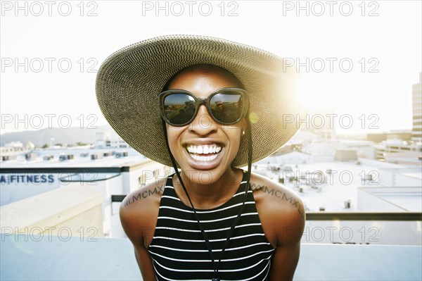 Black woman wearing sun hat and sunglasses on rooftop