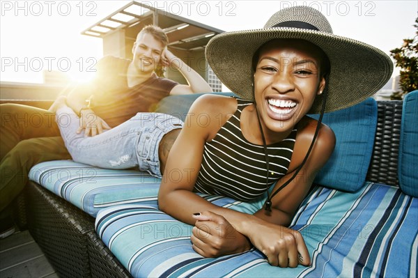 Portrait of smiling couple on rooftop sofa