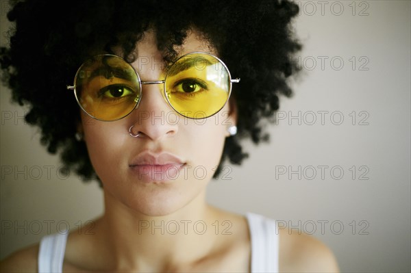 Portrait of serious Mixed Race woman wearing yellow sunglasses