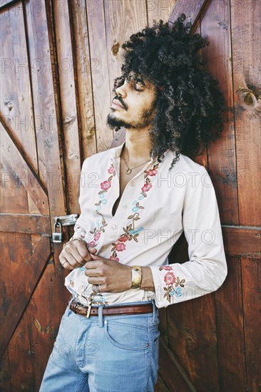 Portrait of Mixed Race man leaning on barn door