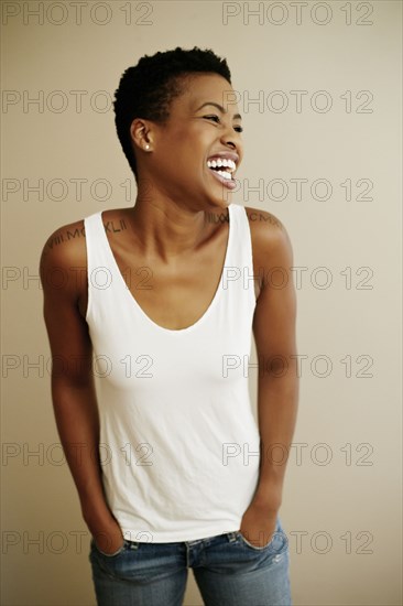 Portrait of laughing Black woman with hands in pockets