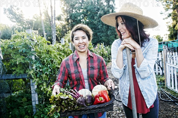 Portrait of women with basket of vegetables in garden