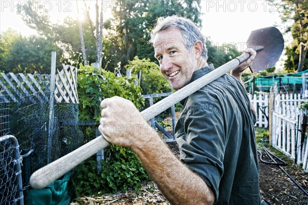 Portrait of Caucasian man carrying shovel in garden