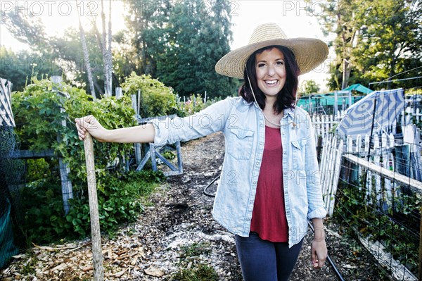 Portrait of Caucasian woman leaning on shovel in garden