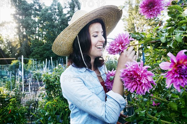 Caucasian woman smelling flower in garden