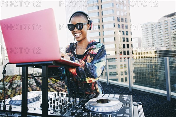 Smiling Black DJ on urban rooftop