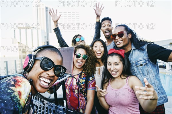 Friends smiling with DJ on urban rooftop