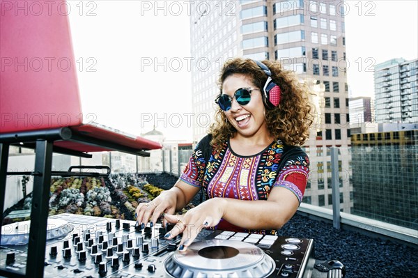 Smiling Mixed Race DJ on urban rooftop