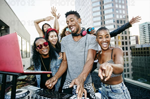 Friends posing with DJ on urban rooftop