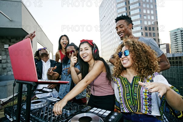 Friends posing with DJ on urban rooftop