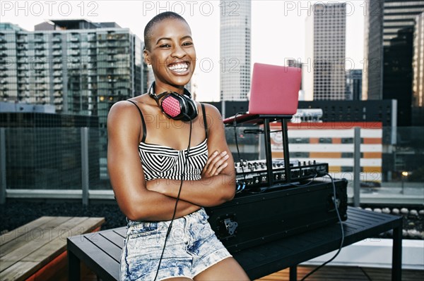 Smiling Black DJ relaxing on urban rooftop